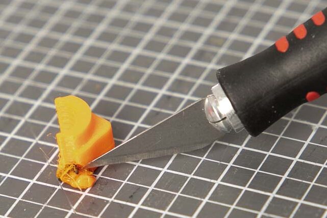 Scalpel cuts off plastic residue from a 3D printed part or component