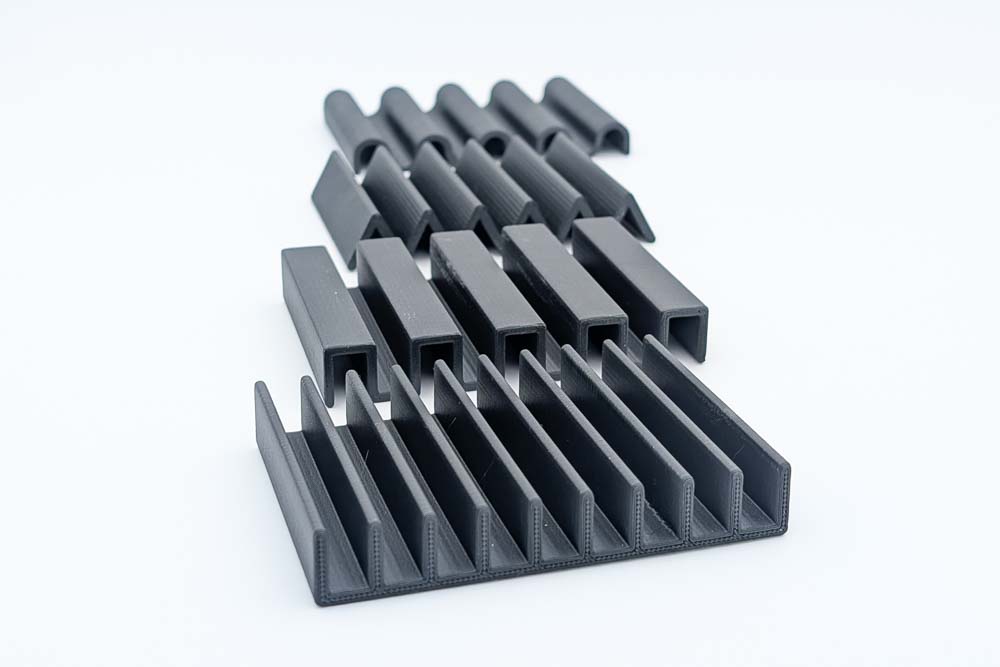 3D printed soap dish, printed in matte black filament, showing the four different designs: Ribbed, Rectangle, Triangle, and Wave.