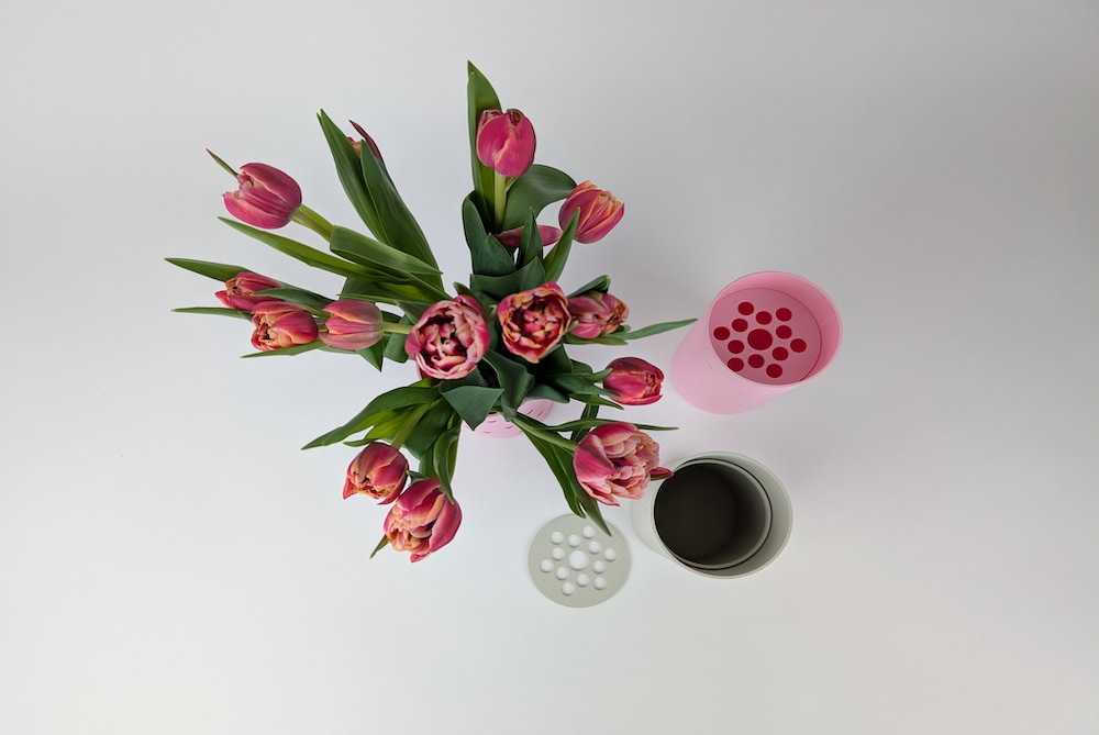 All versions of the 3D-printed heart flower vases, featuring raised red hearts and recessed hearts in pink and beige. All shown from a top-down view, with one vase filled with flowers.
