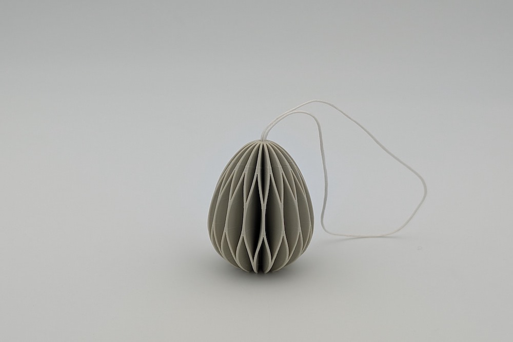 Close-up of a 3D printed Easter egg with string in the color beige, printed with beige filament