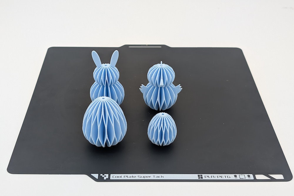3D printed set of Easter ornaments in a honeycomb design (large egg, chick, bunny, small egg) in light blue on the build plate